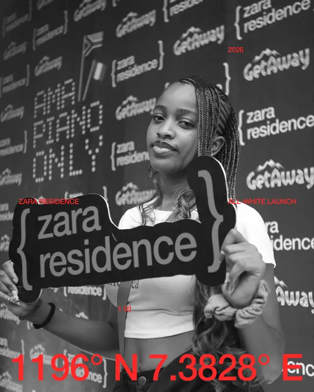 A guest holding the Zara Residence sign at the backdrop